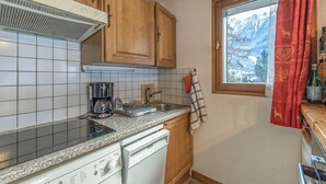 Eine Küche mit Holzausstattung, einer Kaffeemaschine, einem Geschirrspüler und einem Fenster mit Bergblick.