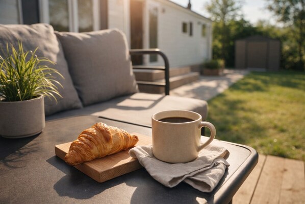A cozy outdoor seating area with a wooden table, a croissant, and a cup of coffee.