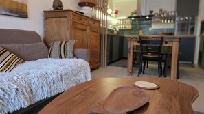 A cozy living room with a sofa, a wooden table, and a kitchen area in the background. - Flat 6 people at the feet of Briançon's ski slopes (Briançon)