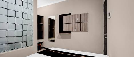 A bedroom with a bed, a wardrobe, a mirror, and a wall-mounted air conditioning unit.