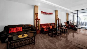 Ein modernes Wohnzimmer mit einer Ledersofa, einem Holztisch und traditionellen Sesseln. An der Wand ist ein rotes Banner mit Text zu sehen.