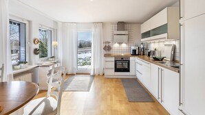 A modern kitchen with white cabinets, a wooden countertop, and a view to the outside. - Apartment Gartenblick, 96 sqm, 2 Bedrooms, Max. 4 Guests (Balve)