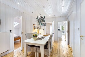A room with a white dining table, wicker chairs, a hanging branch decoration, and a view to a balcony. - Apartment Weitblick, 106 sqm, 3 bedrooms, max. 5 guests (Balve)
