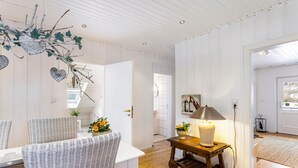 A room with a wicker chair, a small wooden table with a lamp, and a wall-mounted shelf with decorative items. - Apartment Weitblick, 106 sqm, 3 bedrooms, max. 5 guests (Balve)