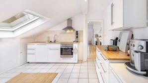 A modern kitchen with a skylight, white cabinetry, a built-in oven, and a coffee machine. - Apartment Weitblick, 106 sqm, 3 bedrooms, max. 5 guests (Balve)