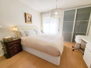 Ein Schlafzimmer mit Bett, Nachttischen, Schreibtisch und Kleiderschrank.