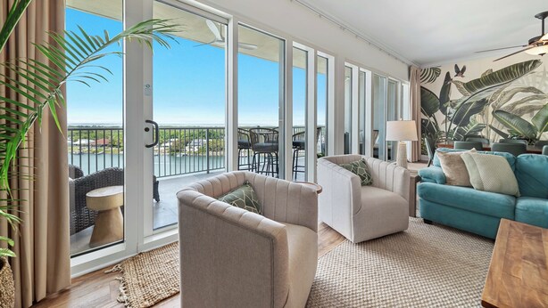 A spacious living area with a balcony, large windows, and a tropical mural. - Sailmakers Place 903 | Two-Story Penthouse | Panoramic Views | My Beach Getaways (Pensacola)