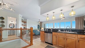 A modern kitchen with wooden cabinets, stainless steel appliances, and pendant lighting. - Sailmakers Place 903 | Two-Story Penthouse | Panoramic Views | My Beach Getaways (Pensacola)