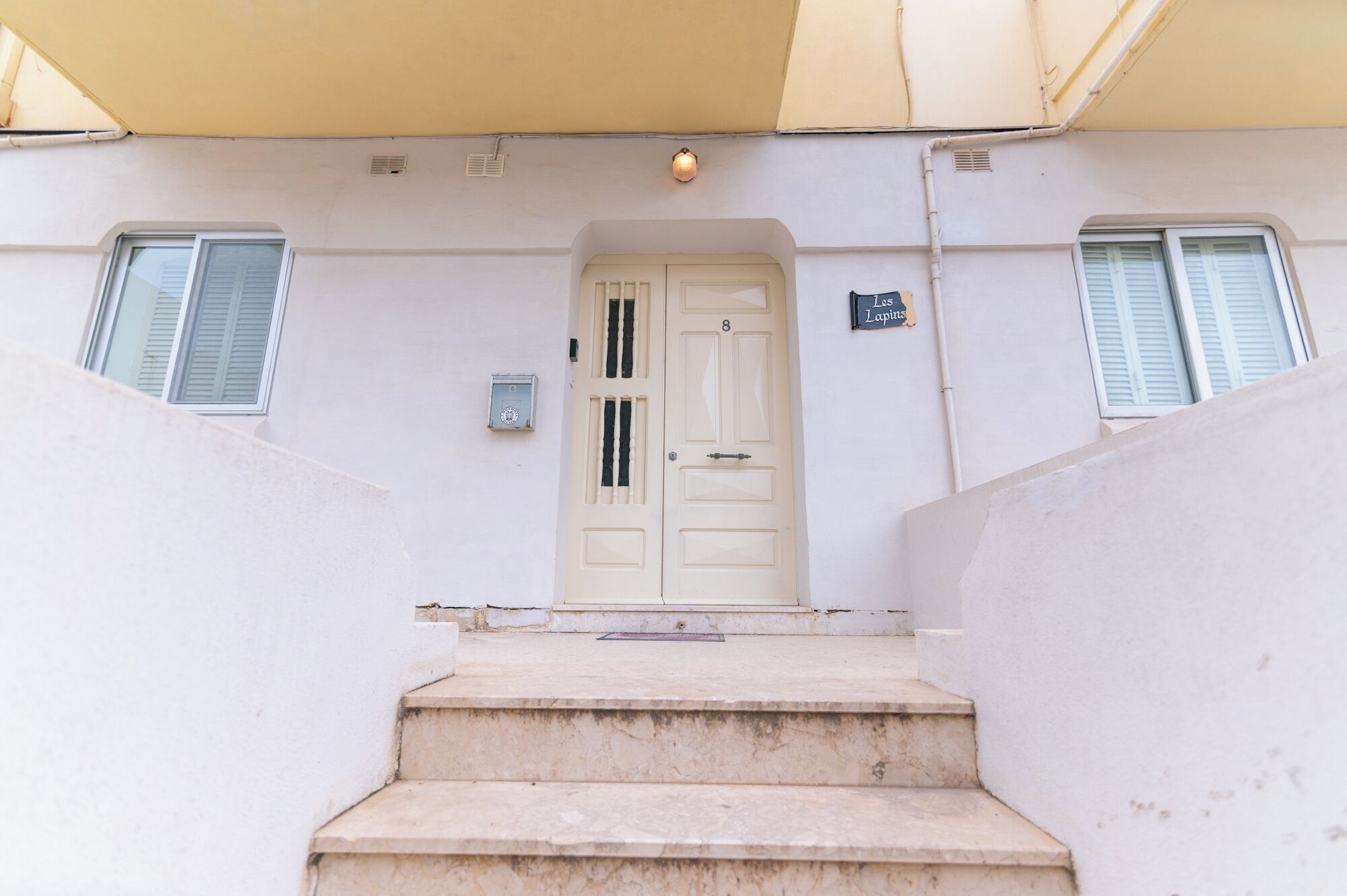 A white building with a beige awning, a white door with the number 8, and a sign reading "Les Lapiers".