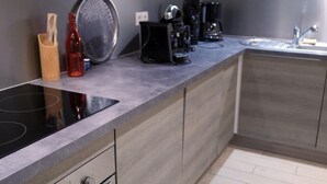 A modern kitchen with a built-in stovetop, a coffee maker, and a kettle.