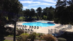 Una piscina grande y curvada rodeada de sillones de descanso y una zona cubierta.