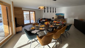 Un comedor moderno con una mesa de vidrio, varias sillas y vistas al exterior.