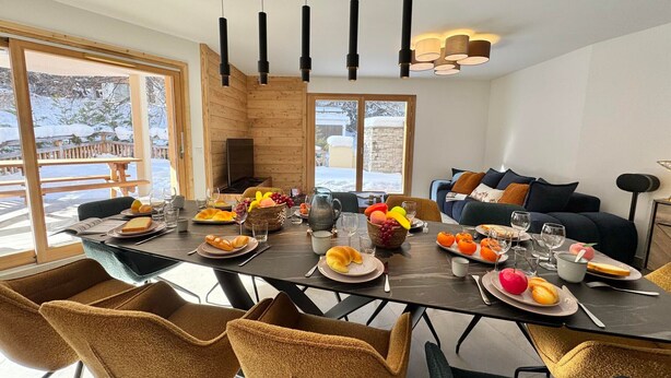 Un comedor moderno con una mesa grande dispuesta para una comida, rodeado de asientos cómodos.