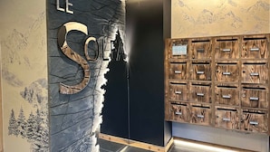 Un área de recepción con un gran letrero 'LE SOLE', una pared negra con un mural de montañas y un sistema de taquillas de madera.