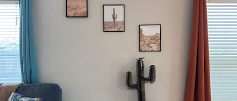 Una habitación con un sofá azul, una escultura de cactus y tres cuadros en la pared.
