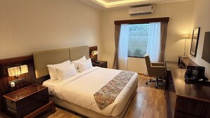 Une chambre d’hôtel avec un grand lit, un bureau, une chaise et un ventilateur de plafond.