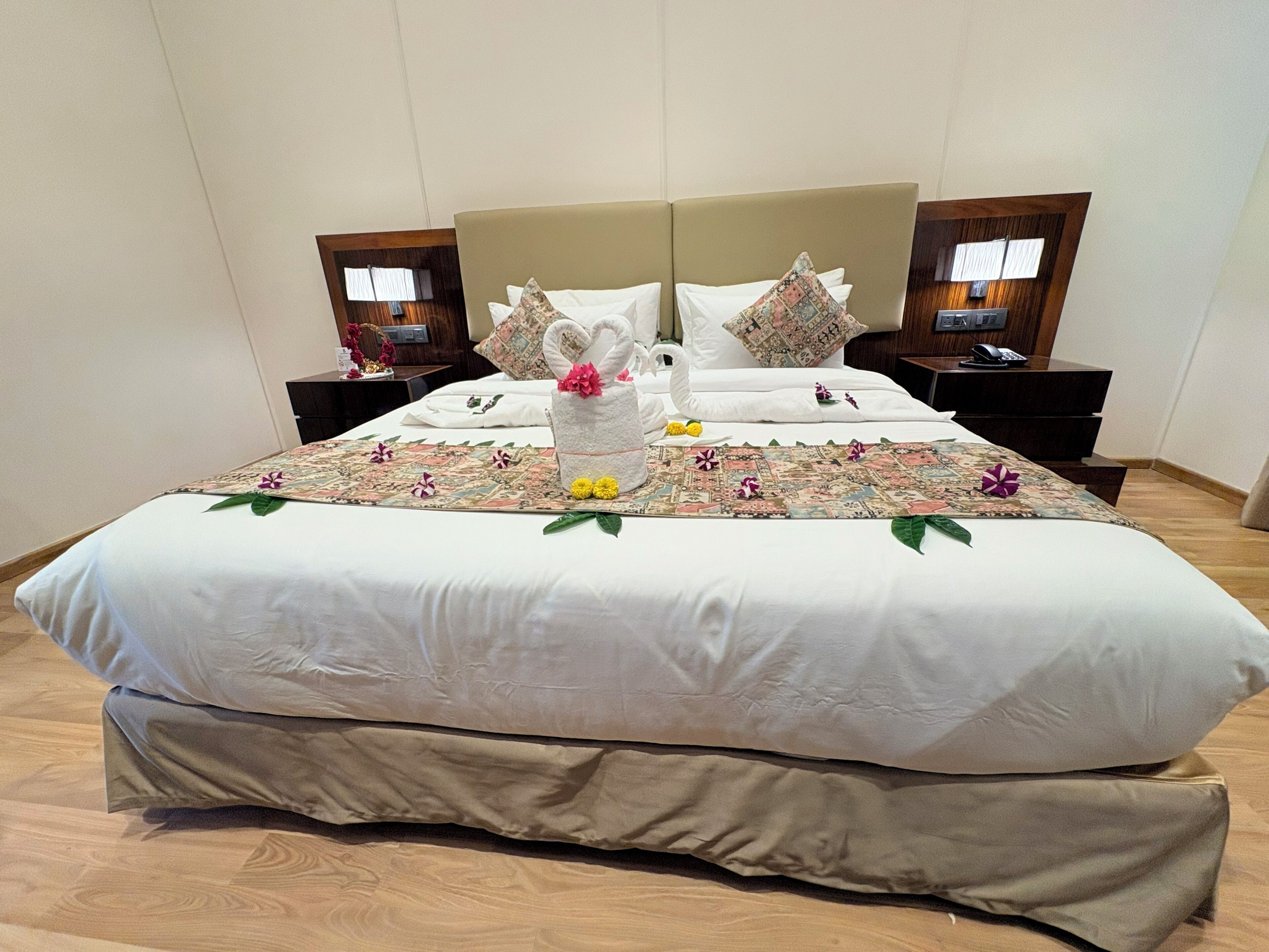 A neatly made bed with a floral-patterned bedspread, two pillows, and a towel arrangement.