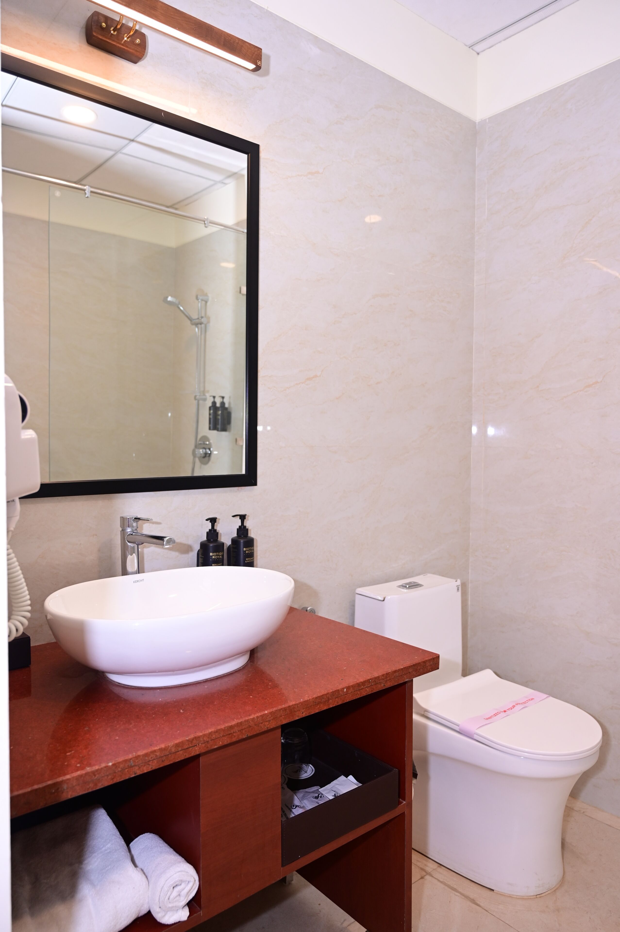 A bathroom with a white sink, mirror, and toilet.