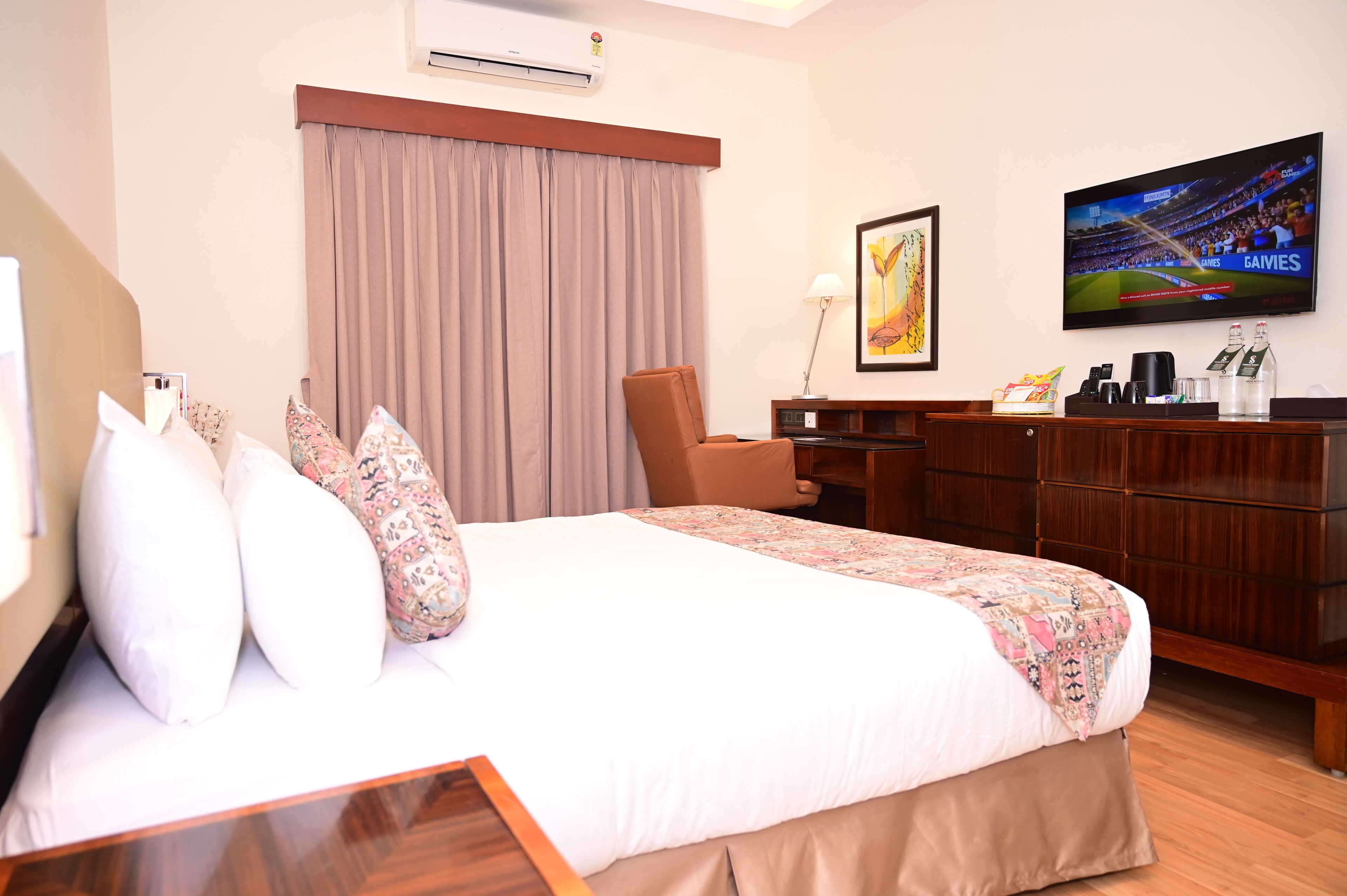 A hotel room with a bed, a desk, a chair, a television, and a window with curtains.