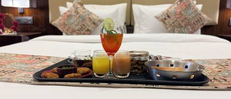 A breakfast tray with various foods and drinks on a bed in a hotel room.
