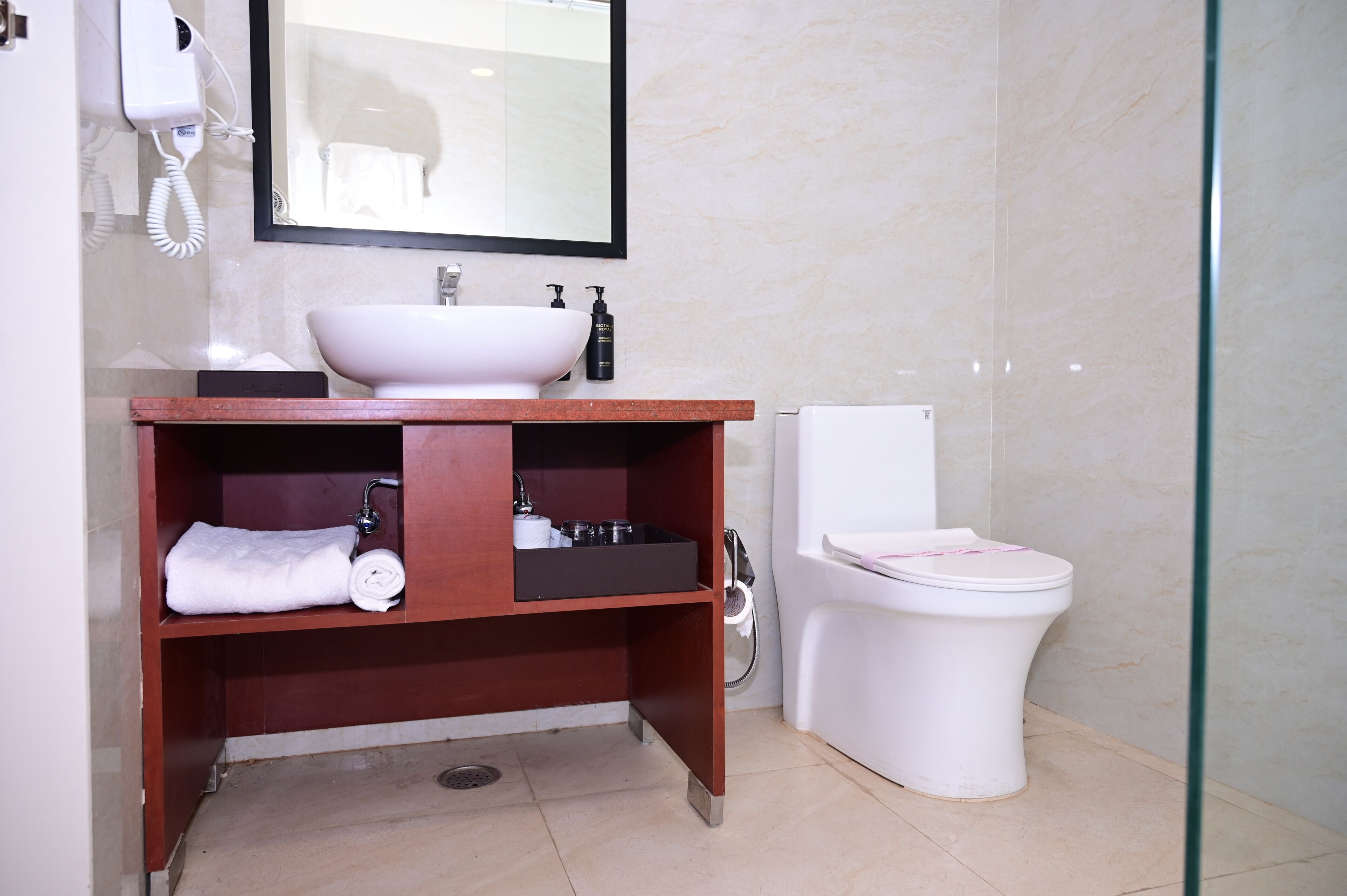 A bathroom with a white sink, a mirror, a toilet, and a shower area.