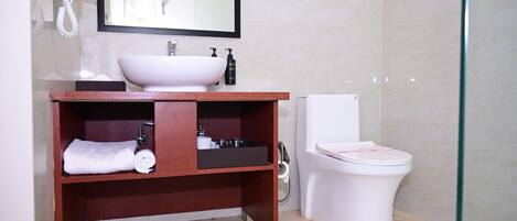 A bathroom with a white sink, a mirror, a toilet, and a shower area.