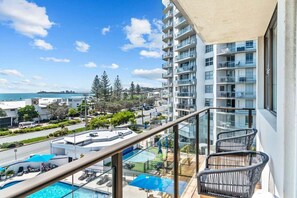 A balcony with a pool, overlooking a cityscape and the sea. - Bright Coastal 3BR Apartment Opposite the Beach (Sunshine Coast)