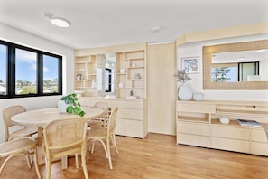 A modern interior with a round dining table, wicker chairs, and built-in wooden shelving. - Bright Coastal 3BR Apartment Opposite the Beach (Sunshine Coast)