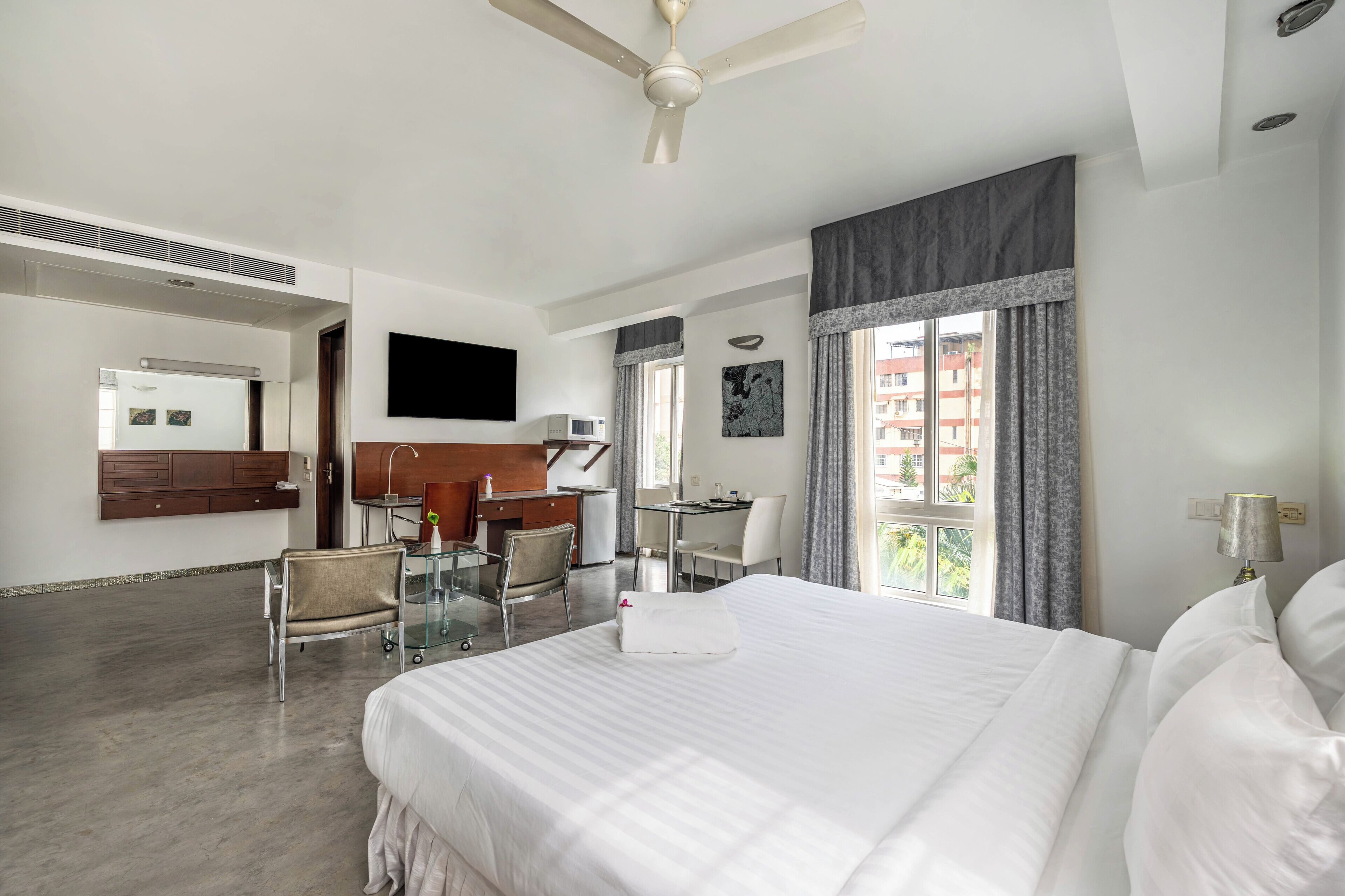 Een hotelkamer met een groot bed, een bureau, een stoel, een televisie en een raam met gordijnen.