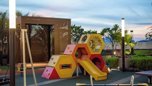 A playground with colorful play structures and a small building in the background. - (Kids Fun) 2BR Space Apt near KSL CIQ JB (Johor Bahru)