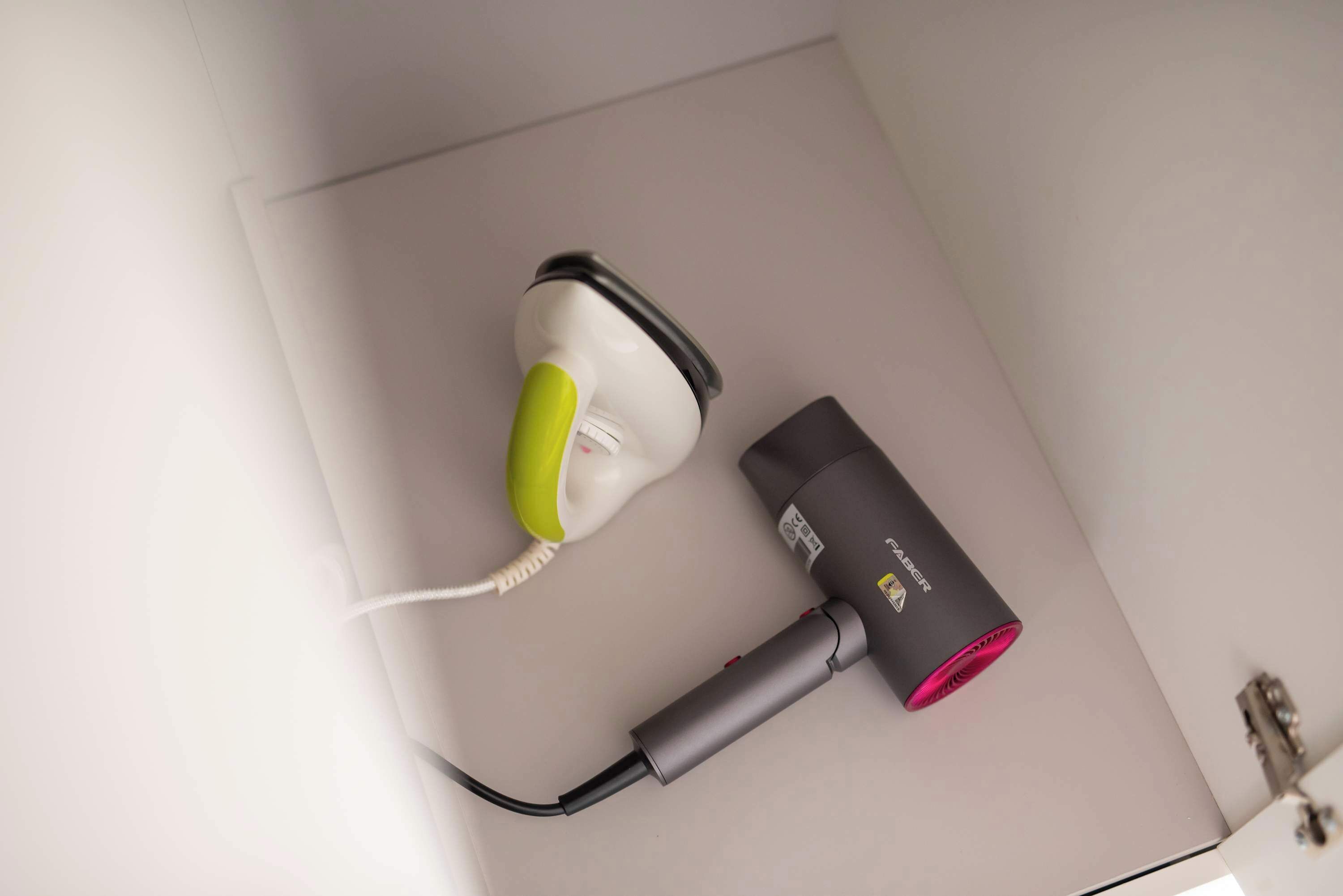 A hairdryer and a phone charger on a white surface.