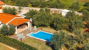 Eine Vogelperspektive auf ein Anwesen mit Swimmingpool, Außenbereich zum Sitzen und einer überdachten Terrasse.
