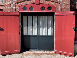 Um edifício de tijolos vermelhos com uma grande porta preta e uma pequena janela acima.