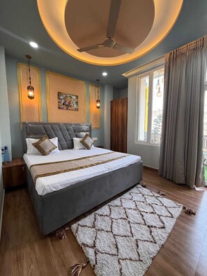 Un dormitorio moderno con una cama grande, un ventilador de techo y un ventanal con cortinas.