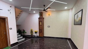 Un hall d’entrée spacieux avec un sol en marbre, un comptoir d’accueil en bois et un escalier.