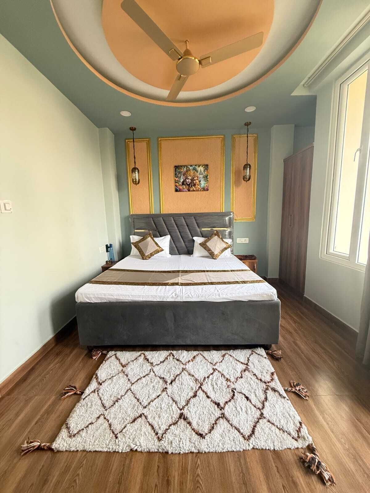 Een slaapkamer met een bed, een plafondventilator, een vloerkleed en een schilderij aan de muur.