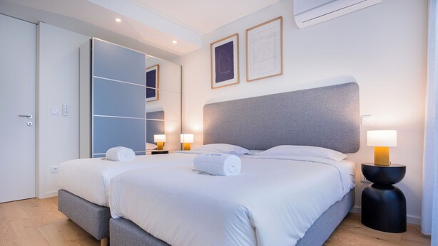 Une chambre d’hôtel moderne avec un grand lit, des lampes de chevet, une armoire et un miroir.