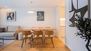 Un salon moderne avec un canapé, une table à manger et des chaises, ainsi qu’une plante en pot.