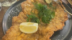 A plate with breaded and fried food, garnished with herbs and lemon.