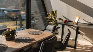 A modern dining area with a wooden table, chairs, a potted plant, and a small table with a picture frame.