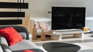 A modern living room with a sofa, a flat-screen TV, and decorative items.