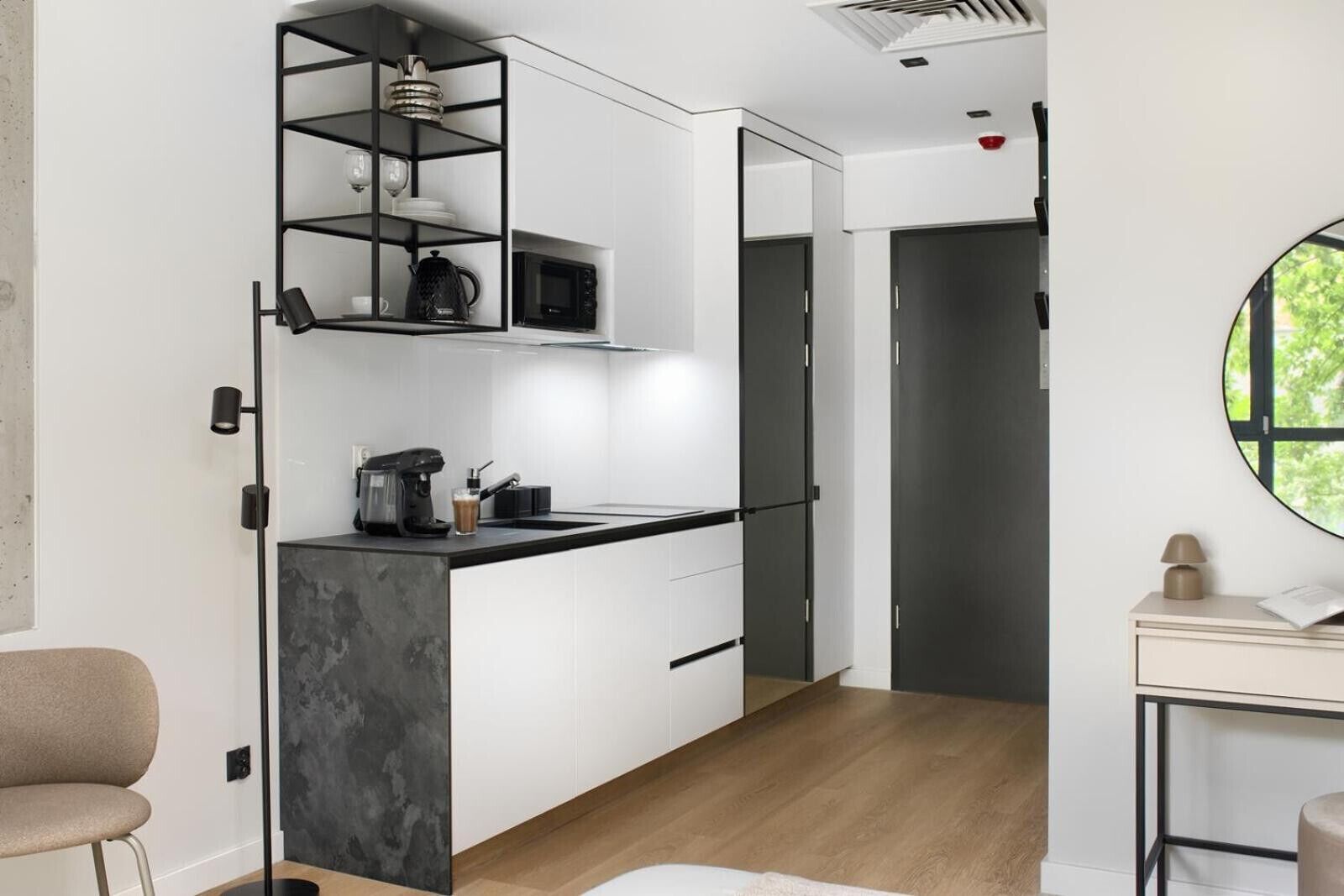 A modern kitchen with a built-in microwave, coffee machine, and a black shelf unit.