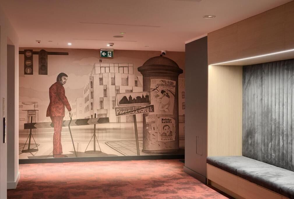 Um hall com um mural, um banco e um pilar com texto.