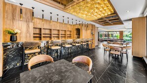 Um restaurante moderno com bancadas de mármore, painéis de madeira e um candelabro. Mesas e cadeiras dispostas para refeições.