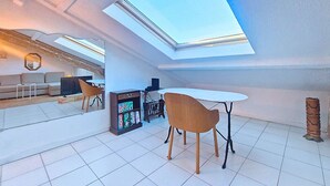 Un salon moderne avec une lucarne, un canapé, une table basse et un téléviseur.