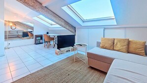 Un salon moderne avec un canapé, un téléviseur et une lucarne.