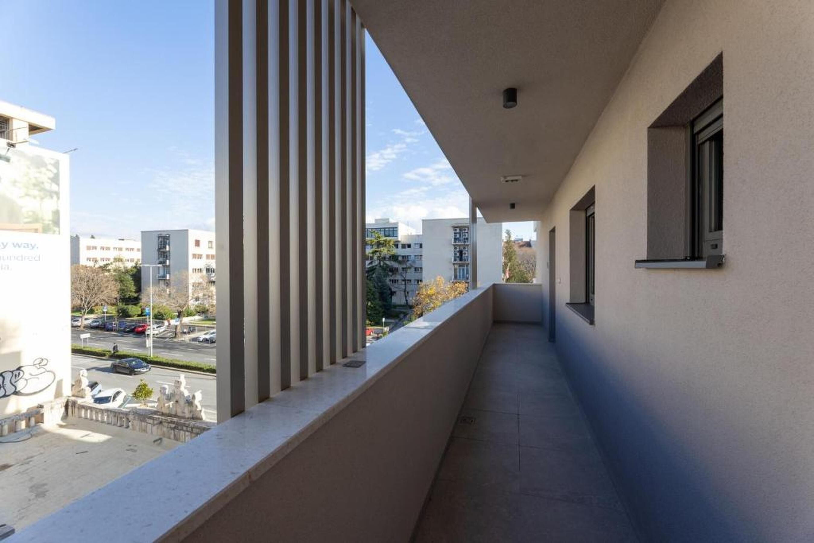 A corridor with a view of a street and buildings, a window, and a door.