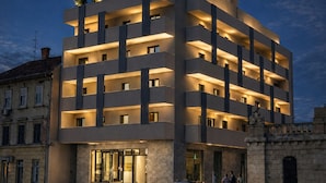 A multi-story hotel with a modern design, featuring balconies on the upper floors and a central entrance with glass doors.