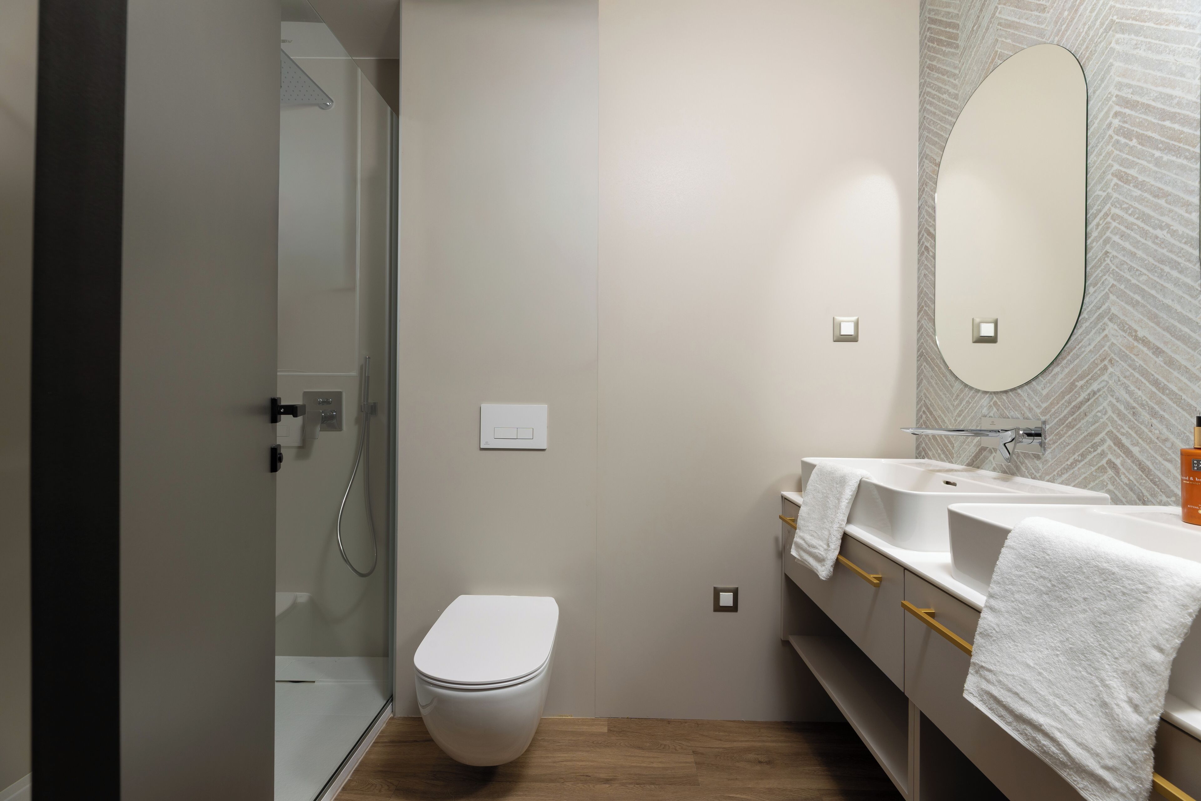 Une salle de bain moderne équipée de toilettes, d’une douche et de deux lavabos, ainsi que de serviettes.