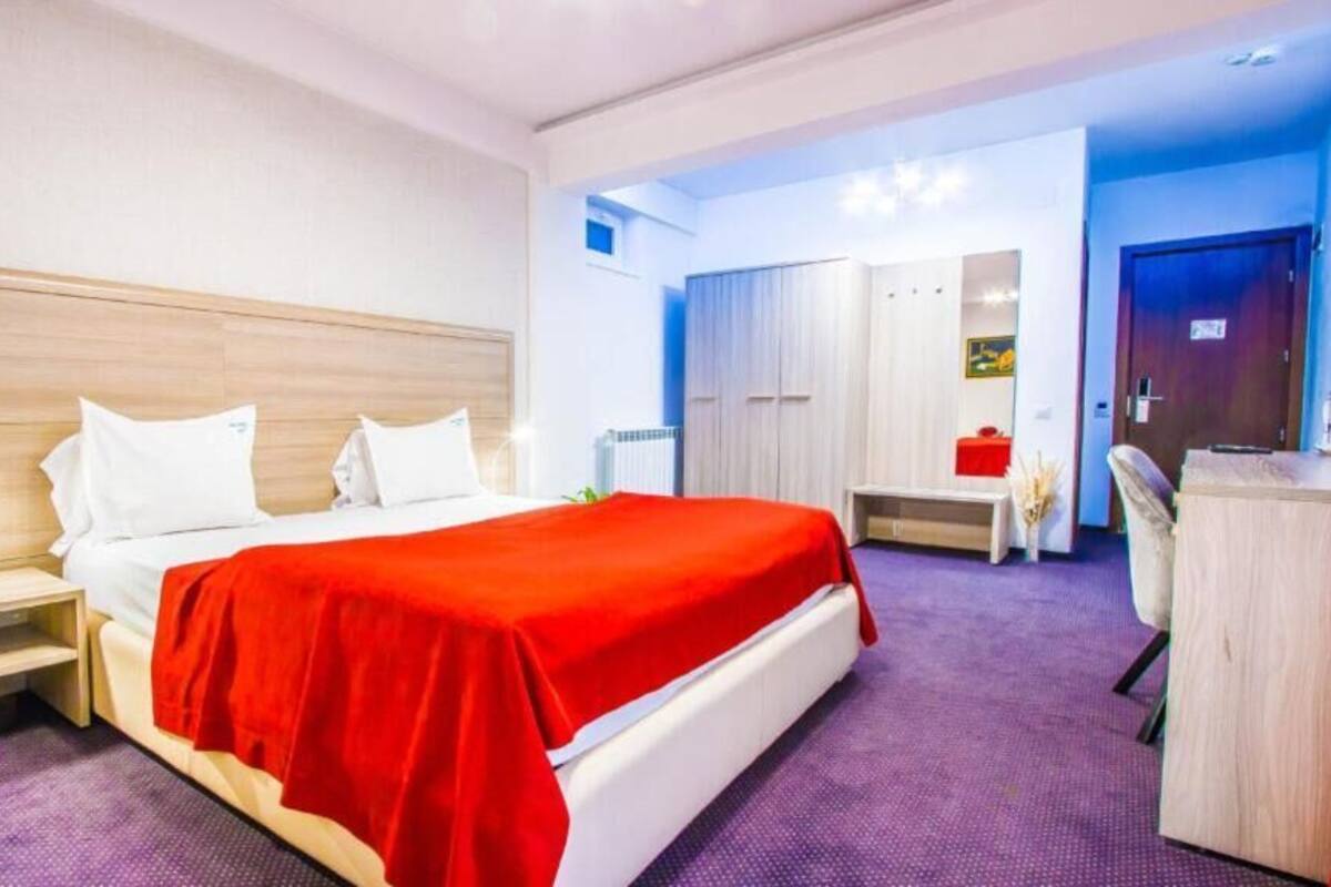 Ein Hotelzimmer mit einem Bett, Nachttischen, einem Schreibtisch und einem Stuhl.